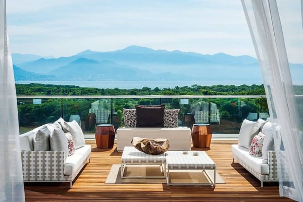 Balcón frente al mar con asientos, terraza de madera y vistas a un lago de montaña tras una barandilla de cristal